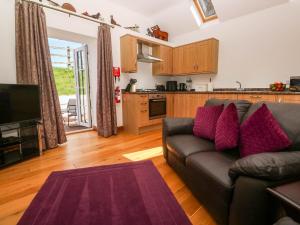 a living room with a couch and a kitchen at The Coach House in Hayle