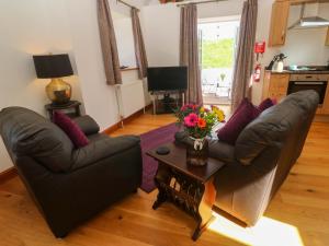 a living room with two couches and a table with flowers at The Coach House in Hayle