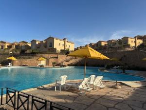 a swimming pool with chairs and an umbrella and a pool at lavista cozy chalet one bedroom in Ain Sokhna