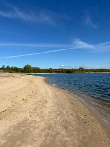 a sandy beach with water and trees in the background at In Seenähe - Modernes Chalet im Ferienpark De Veerstal - familienfreundlich! in Lathum