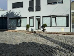 a building with windows and a brick driveway at Albergue Pilares do Caminho in Marinhas