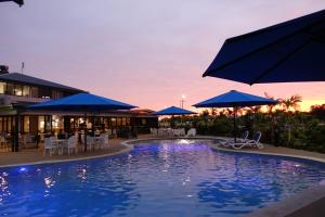 uma piscina com guarda-sóis azuis, mesas e cadeiras em Quality Resort Parkhurst em Rockhampton