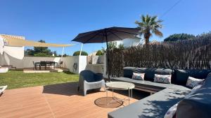 a patio with a blue couch and an umbrella at Galo - Private Pool - 8 Guests - Albufeira in Albufeira
