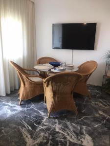 een eettafel met rieten stoelen en een flatscreen-tv bij ARIS House in Agia Paraskevi