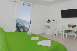 a white room with a green bed and a desk at Amalfi Montemare Rooms in Amalfi