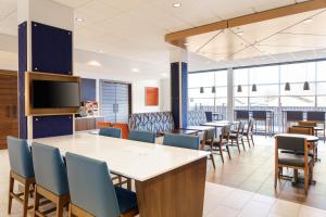 Un comedor con mesas y sillas y un televisor. en Holiday Inn Express & Suites Westfield - Indianapolis by IHG, en Westfield