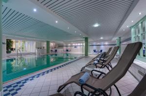 a pool with lounge chairs next to a swimming pool at Hotel Aquamarin in Kühlungsborn