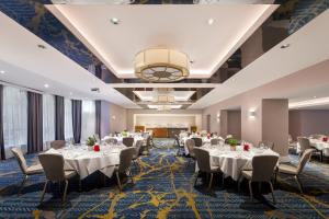 a banquet room with tables and chairs and a chandelier at Crowne Plaza Gerrards Cross by IHG in Beaconsfield