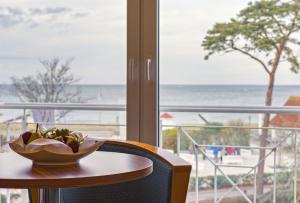a bowl of fruit on a table with a view of the beach at Hotel Aquamarin in Kühlungsborn