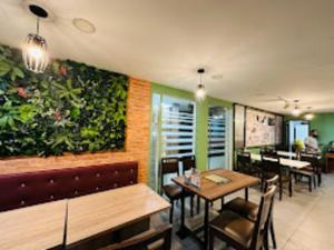 a restaurant with tables and chairs and a green wall at Orkid Hills Hotel at Bukit Bintang in Kuala Lumpur