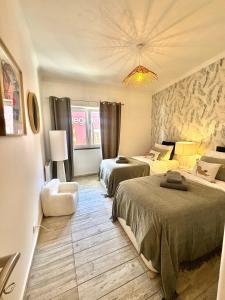 una camera d'albergo con due letti e un lampadario a braccio di FM Herculano - Sea, Sun & Fun a Cascais