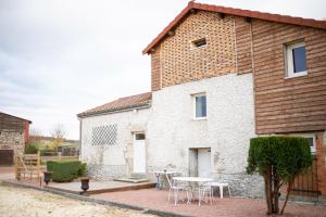 a building with a table and chairs in front of it at Le petit paddock in Villeneuve-lès-Cerfs