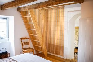 a bedroom with a wooden staircase next to a bed at Le petit paddock in Villeneuve-lès-Cerfs +18 photos