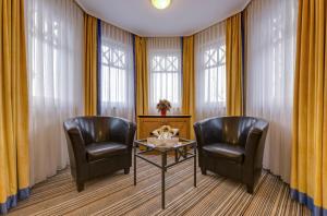 two chairs and a table in a room with windows at Hotel Aquamarin in Kühlungsborn