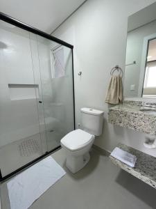 a white bathroom with a toilet and a shower at R1 - Iguaçu Apt - Centro of Foz in Foz do Iguaçu
