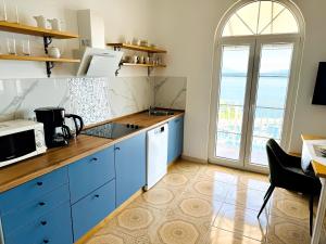 a kitchen with blue cabinets and a large window at Die Appartements Glavas mit Loggia und Balkon für 3 Personen in Novi Vinodolski +23 photos
