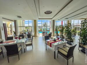 a dining room with tables and chairs and windows at Hôtel MENABE'L in Antsirabe