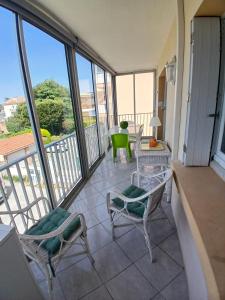 einen Balkon mit 2 Stühlen und einem Tisch sowie einigen Fenstern in der Unterkunft Petit Paradis aux Lones 2 min de la plage 3 chambres clim parking aperçu mer in Six-Fours-les-Plages