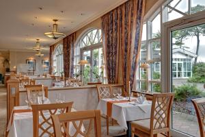 a restaurant with tables and chairs and windows at Hotel Aquamarin in Kühlungsborn