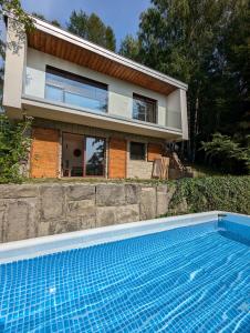 a house with a swimming pool in front of a house at Modernistyczna willa poety i aktorki, z widokiem na jezioro i góry oraz prywatnym basenem, sauną, kominkiem, lasem i ogrodem in Rożnów