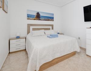 biała sypialnia z łóżkiem i telewizorem w obiekcie Studio RELAX playa del Cura, Felix Rodriguez 3 w mieście Torrevieja