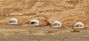 a group of domes in front of a rocky mountain at Eram camp in Jurf ad Darāwīsh