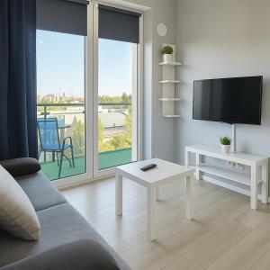 un salon avec un canapé, une télévision et une table dans l'établissement Urban Jungle - Silver Apartment, à Białystok