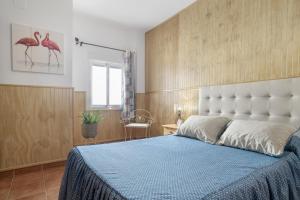 a bedroom with a large bed with a blue blanket at Apartamento Frank - solo familias in Conil de la Frontera