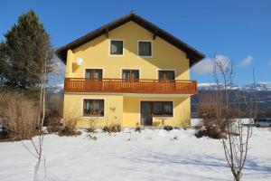 ein gelbes Haus mit Balkon im Schnee in der Unterkunft Haus Mup in Spittal an der Drau