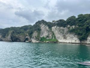 a boat in a body of water with a mountain at IZU Elysian View in Koura