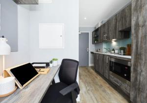 a kitchen with a wooden table with chairs and a laptop at For Students Only - Collegiate Crown Place Cardiff in Cardiff