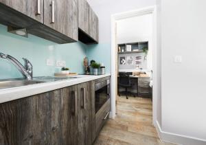 a kitchen with wooden cabinets and a desk in the background at For Students Only - Collegiate Crown Place Cardiff in Cardiff