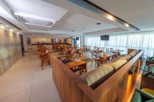 a restaurant with wooden tables and chairs in a room at Hotel Village Confort in João Pessoa