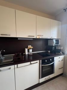 una cucina con mobili bianchi, un lavello e una stufa di Apartment Chocolate Ravda a Ravda Altre 5 foto