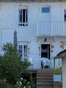 una casa bianca con sedia e ombrellone di Les Vagues a Saint-Gilles-Croix-de-Vie