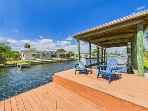 two blue chairs sitting on a dock next to the water at Dolphins In The Backyard & Rockets In The Sky in Merritt Island