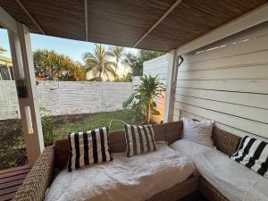 a couch sitting on a porch with pillows on it at Villa Pétrel in Saint-Paul
