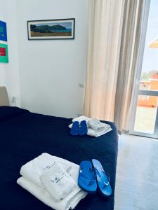 a hotel room with a bed with blue flip flops and towels at Villa Lina in Castiglioncello