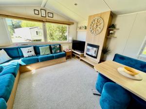 a living room with a blue couch and a table at 3 Bedroom Caravan with Decking at Newquay Bay Resort in Porth