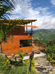 a wooden house with a deck and mountains in the background at Cabaña con vistas a la montaña in Cachipay