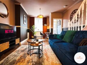 a living room with a blue couch and a tv at Mariposa House - A Tasteful Escape in South Wales in Abertillery