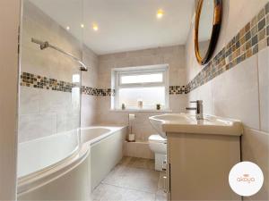 a bathroom with a tub and a toilet and a sink at Mariposa House - A Tasteful Escape in South Wales in Abertillery
