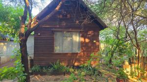 a small wooden house with a window in a yard at Mokolodi Conservancy Chalets in Gaborone