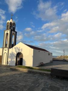 a church with a clock tower with a bench in front at Studio La Caleta De Interian Garachico in Caleta de Interián