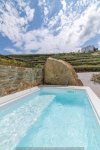 a large swimming pool with a large rock at Rockaine Suites Echoes in Tinos