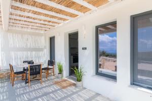 a patio with a table and chairs and a view of the ocean at Rockaine Suites Echoes in Tinos
