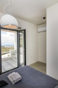 a bedroom with a bed and a large window at Rockaine Suites Echoes in Tinos +22 photos