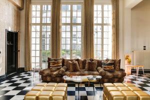 - un salon avec un canapé et de grandes fenêtres dans l'établissement Small Luxury Hotel De Witte Lelie, à Anvers