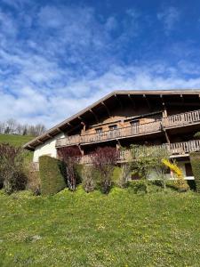 a building on a hill with a green field at CHALET LE REPAIRE PROCHE PISTE in Megève