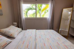 a bedroom with a bed and a window with a palm tree at The little Heaven in Baie Nettle
